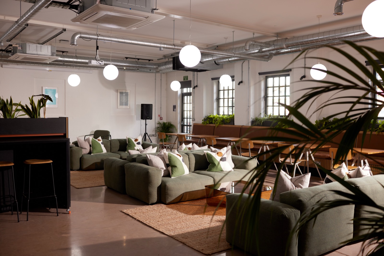 The main co-working hall with green seating under white roof trusses