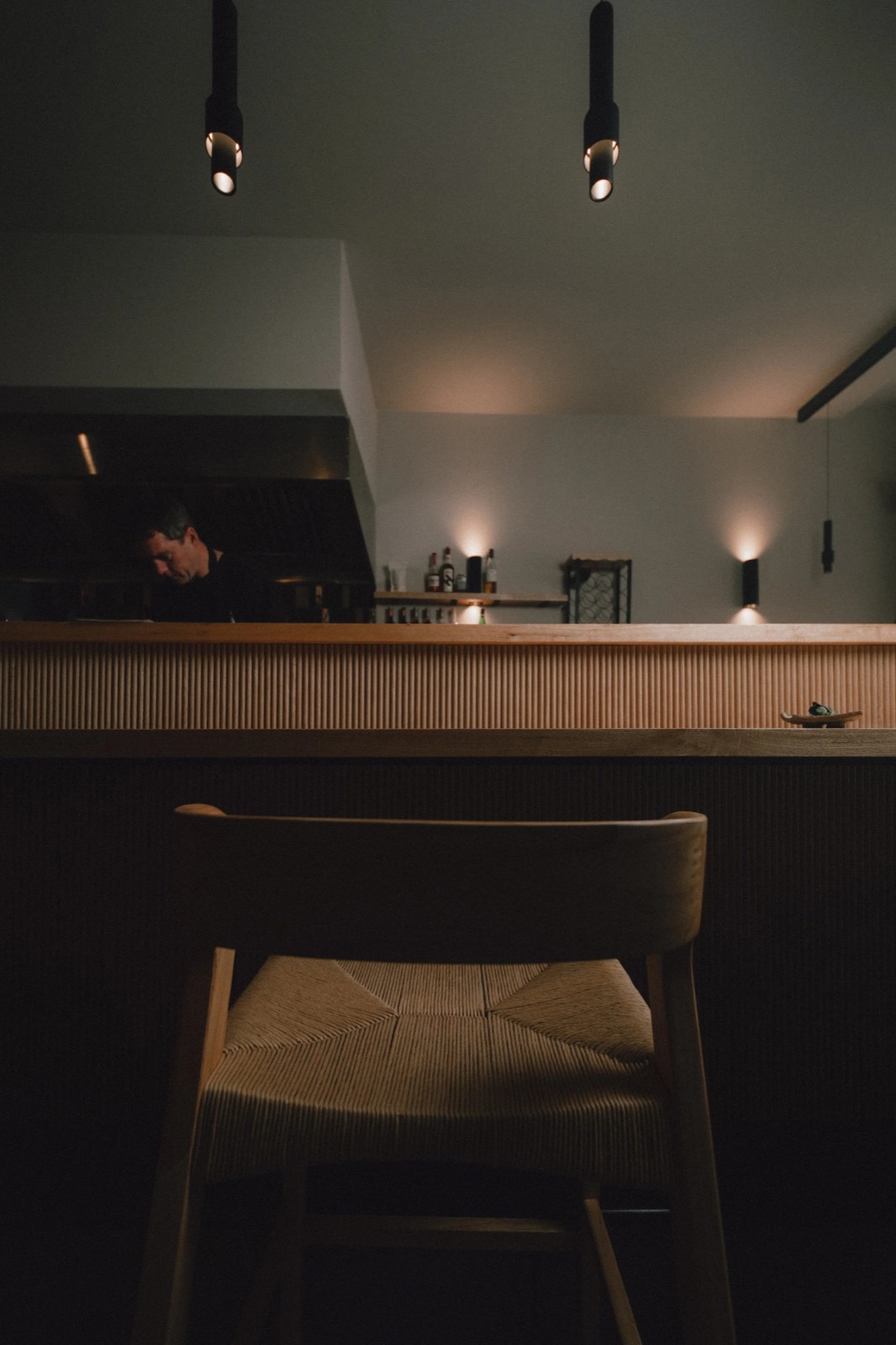 A woven-seat stool at the counter, the kitchen beyond