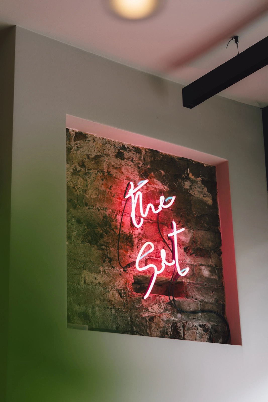 The neon sign in a recess of bare brick